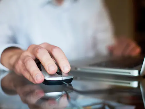 Close up of a person's hand using a computer mouse.